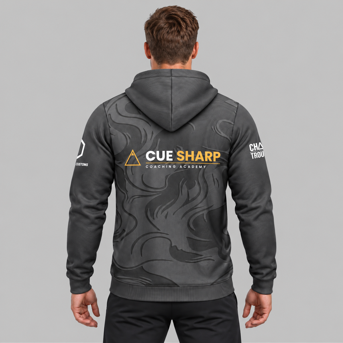 Back view of the Official Cue Sharp Coaching Unisex Hoodie, showing the plush dark charcoal hood, relaxed athletic back paneling, and subtle upper collar branding.