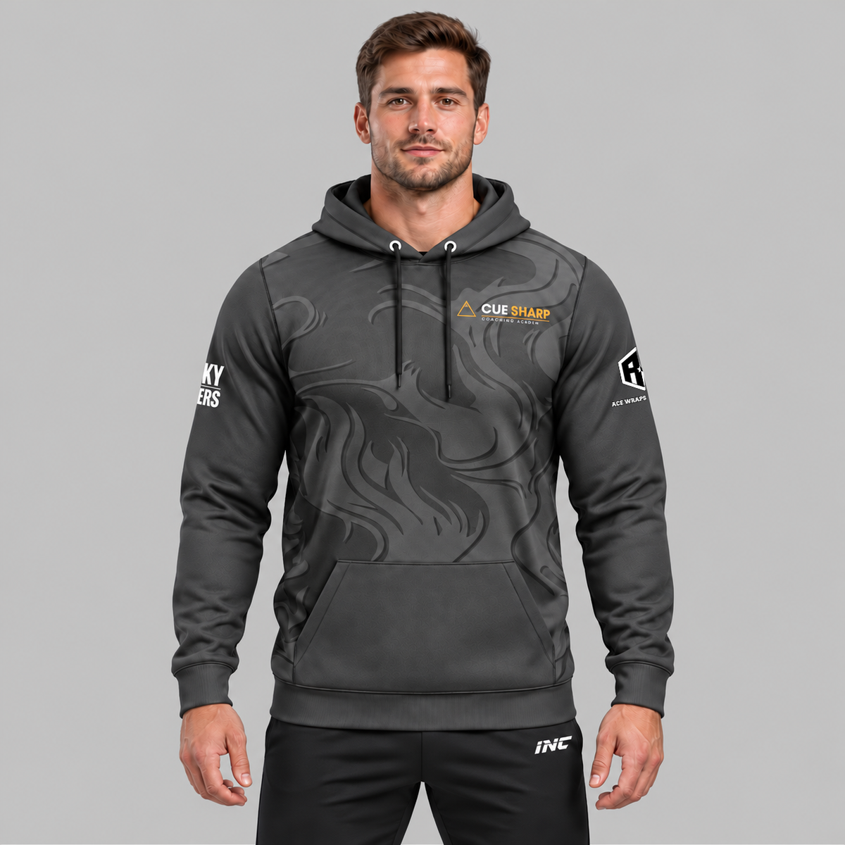 Front view of the Official Cue Sharp Coaching Unisex Hoodie, featuring dark charcoal fabric with gold accents, kangaroo pocket, official Cue Sharp chest logo, and Controlled Climate hem detail.