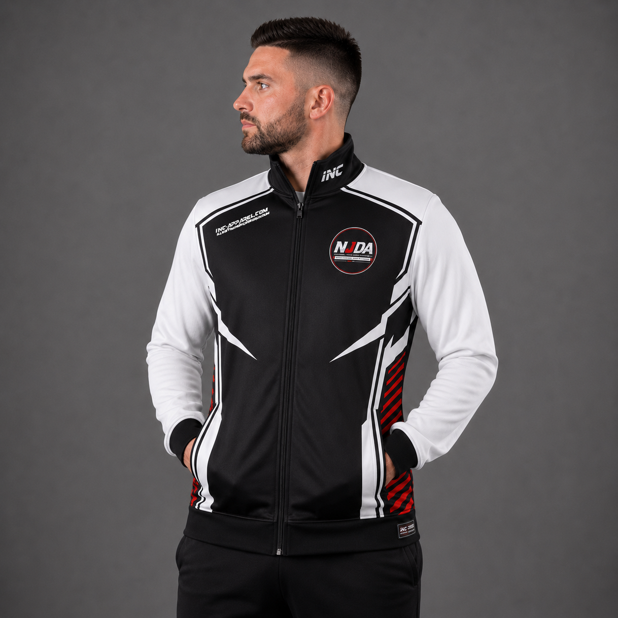 Official National Junior Darts Association tournament jacket in white and black, showing a full-zip presentation design with the embroidered NJDA logo, ribbed cuffs, and zipped pockets.
